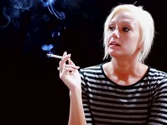 Смазливая блондинка курит сигарету и сосет член