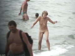 Вуайерист подсматривает на пляже за голой красивой блондинкой